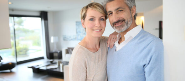 Smiling middle-aged couple standing in brand new home